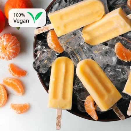 Orange mandarine-flavored popsicles on wooden sticks engraved with "Pop City," placed on a bed of ice cubes in a bowl, surrounded by peeled mandarine segments and whole mandarins, with a "100% Vegan" label in the top left corner.