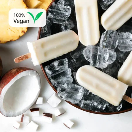 Creamy white Pina Colada popsicles on a bed of ice cubes, surrounded by pieces of coconut and pineapple, with "Pop City" engraved on the sticks and a "100% Vegan" label in the top left corner.