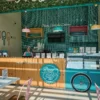 Interior of a colorful and inviting Popcity shop, featuring a wooden counter with a turquoise panel, a bicycle wheel, and the shop's name in English and Arabic.