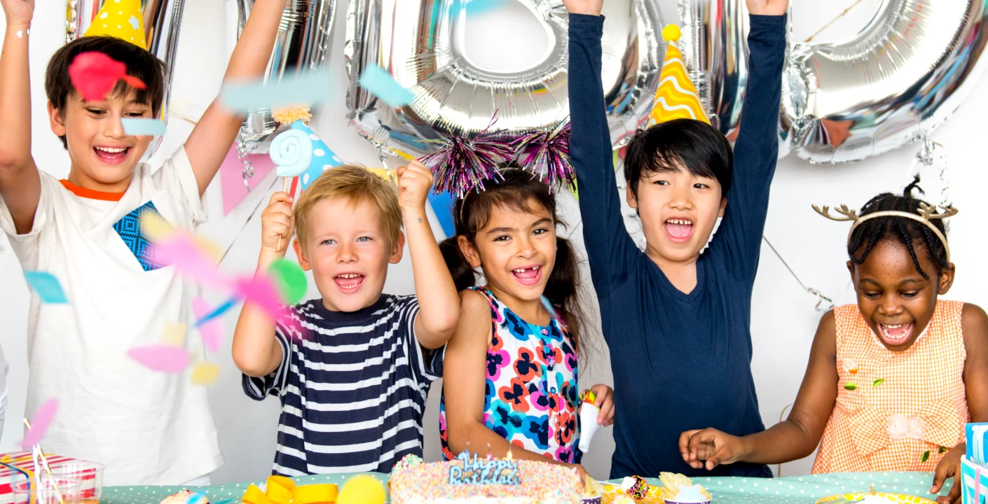 Children celebrating a birthday party with colorful decorations and a table full of treats