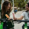 Two people enjoying popsicles while riding scooters outdoors in Dubai summer
